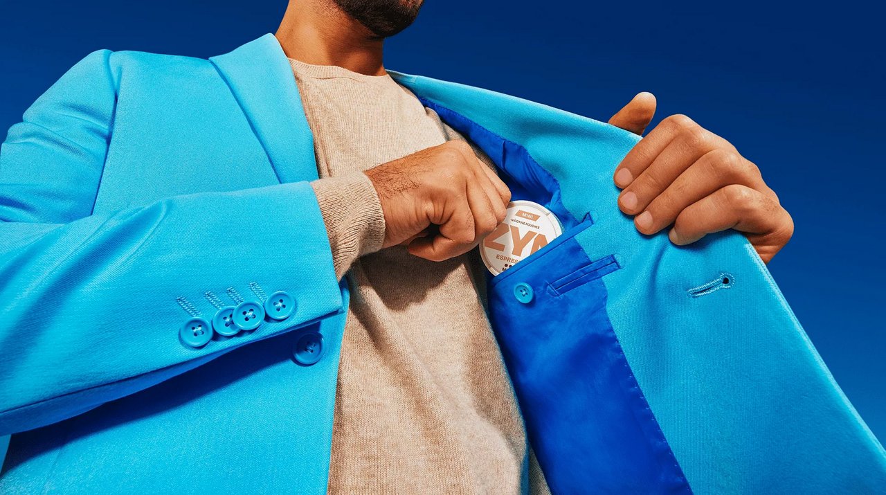 Person steckt eine ZYN-Dose in die Innentasche eines blauen Blazers.