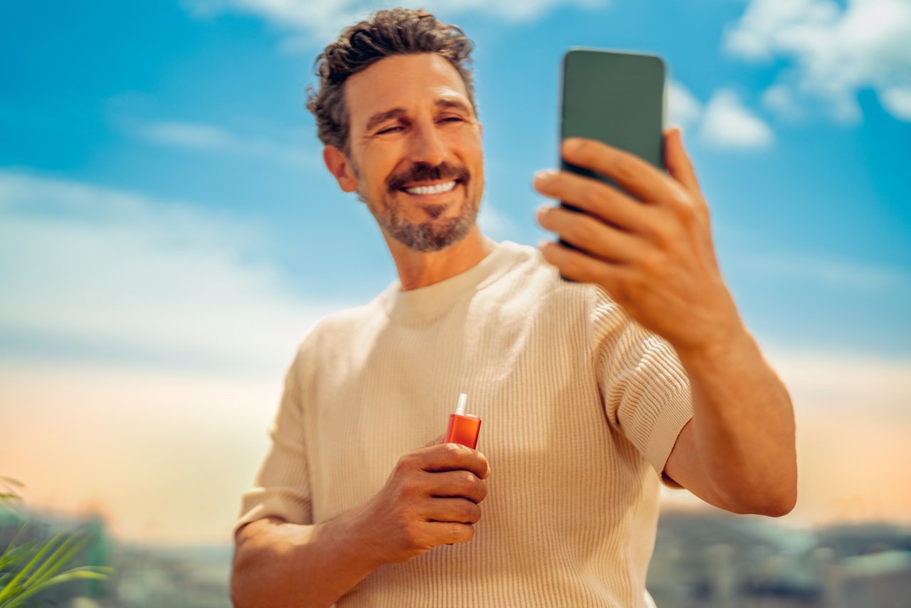 Man holding IQOS ILUMA ONE device using a laptop 