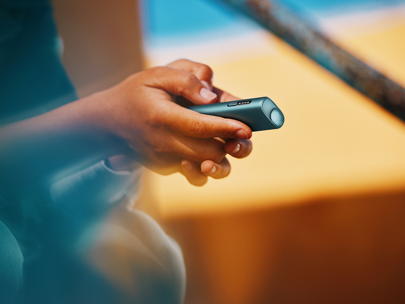 A person holding an IQOS ILUMA ONE color Breeze Blue in their hand
