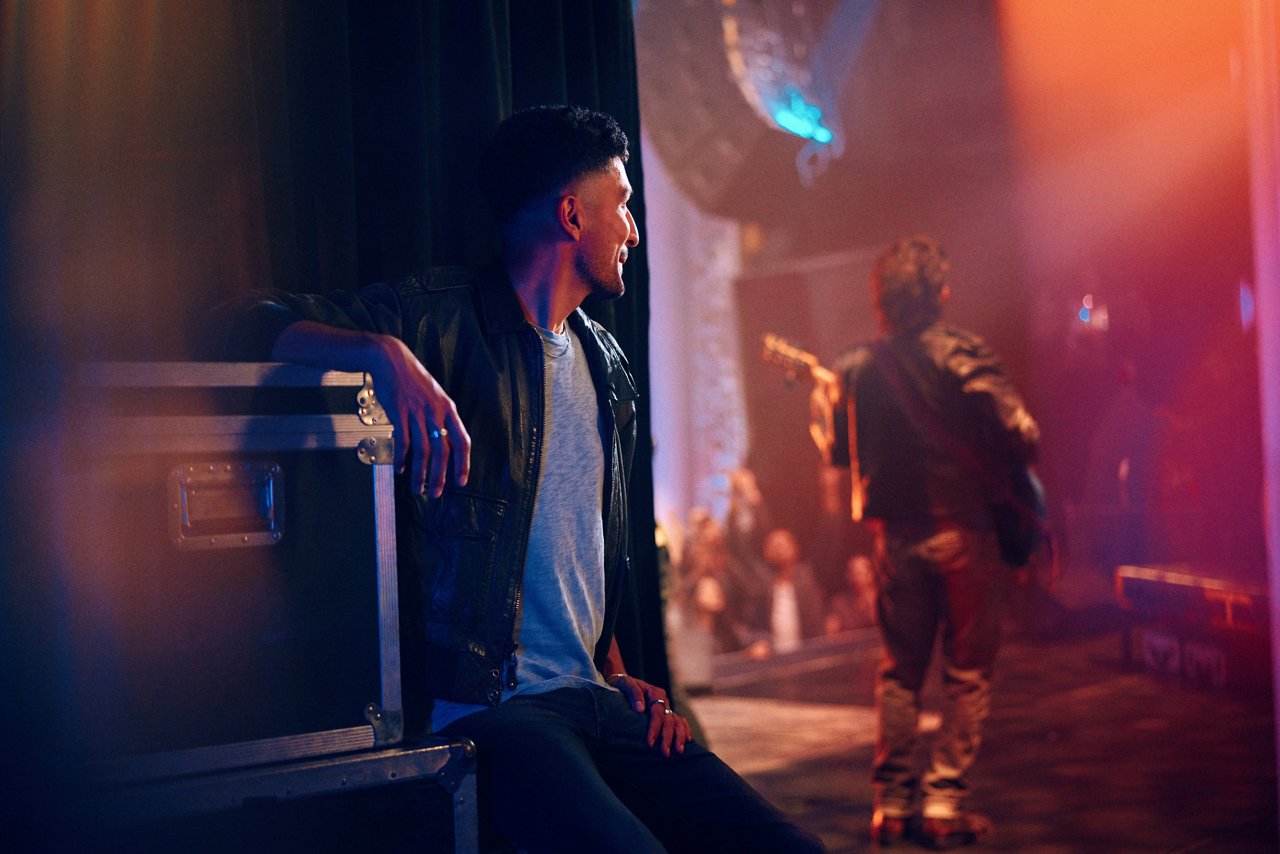 Hombre sentado en un concierto mirando al guitarrista