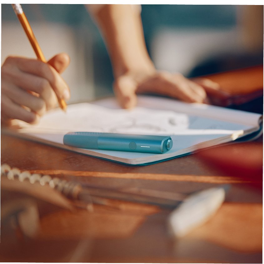 IQOS ILUMA i ONE color Breeze Blue encima de un cuaderno