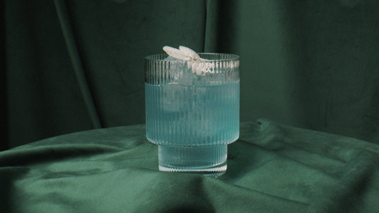 Ein Getränkt mit Zierblüten vor einem fotografisch drapierten Hintergrund