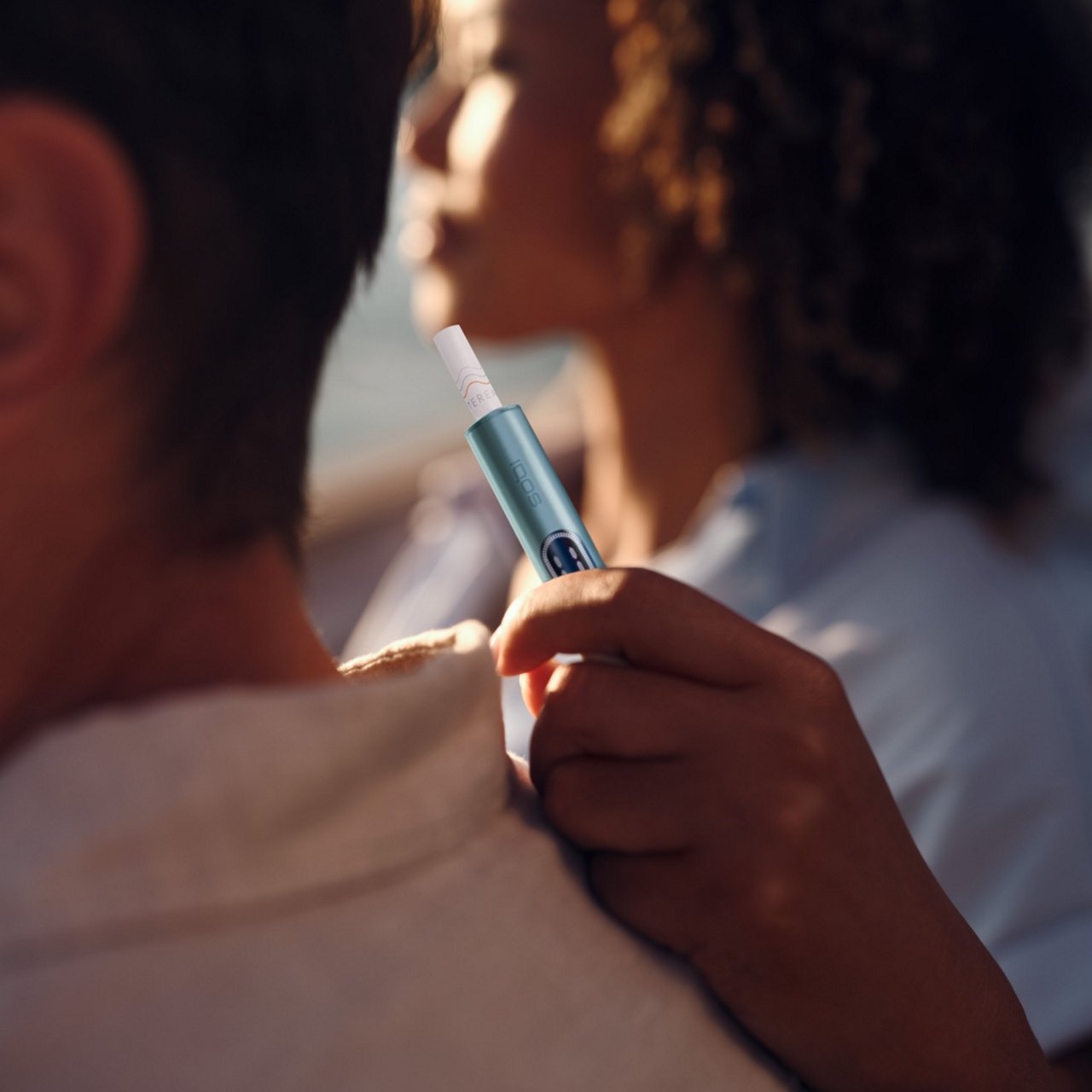 A hand holding blue IQOS ILUMA i