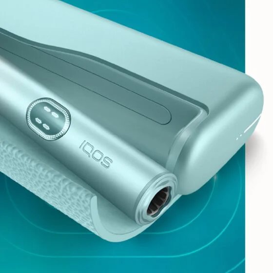 عرض قريب لجهاز IQOS ILUMA i PRIME بلون أخضر نعناعي أنيق، يُظهر حامل الجهاز والشاحن بتصميم عصري محكم.