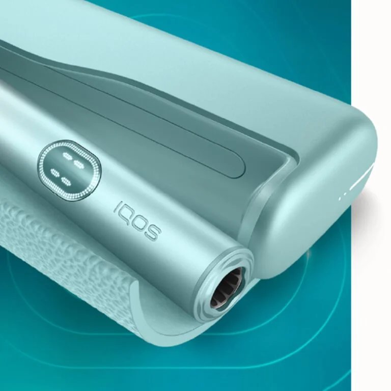 عرض قريب لجهاز IQOS ILUMA i PRIME بلون أخضر نعناعي أنيق، يُظهر حامل الجهاز والشاحن بتصميم عصري محكم.
