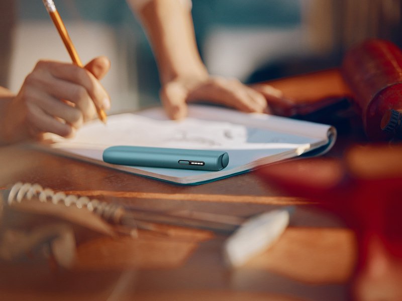 IQOS ILUMA i ONE color Breeze Blue encima de un cuaderno