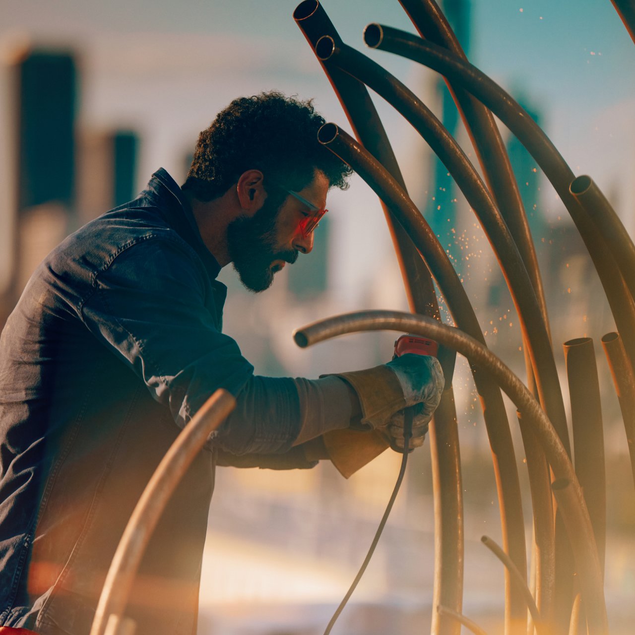 Hombre trabajando con tubos metálicos al aire libre sin dispositivo visible.