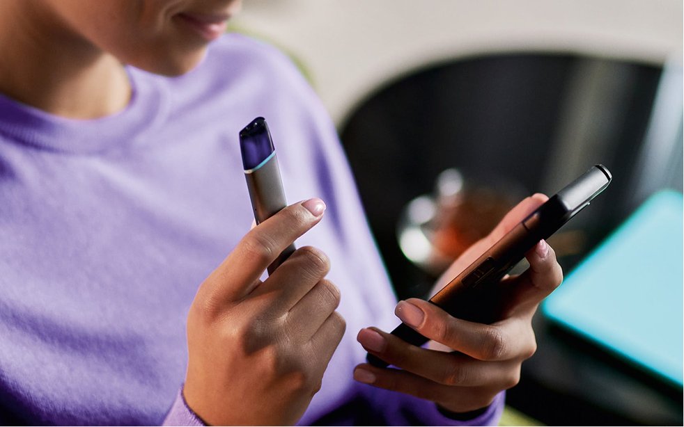 Frau mit VEEV und Smartphone in den Händen.