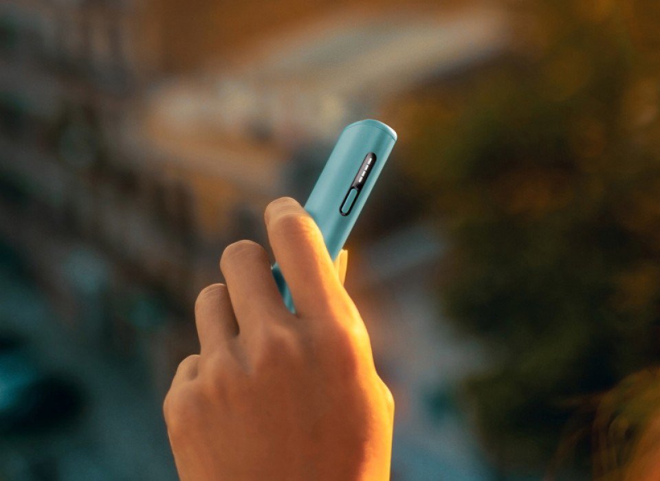 Hand holding a blue IQOS ILUMA i device.