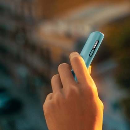 Hand holding a blue IQOS ILUMA i device.