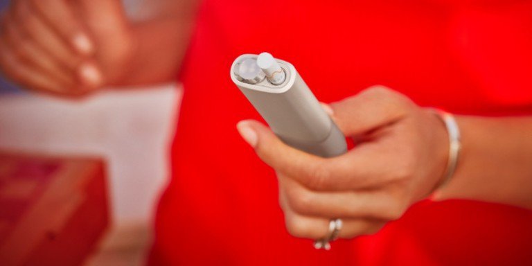 Hands unboxing an IQOS device.