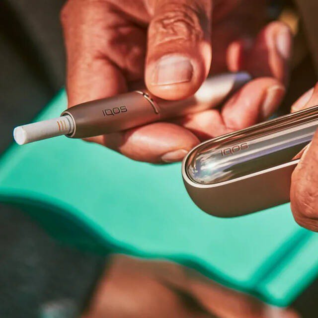 Brilliant gold IQOS 3 DUO holder with HEETS stick and charger in hand