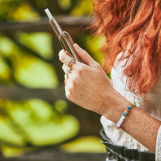 A red hair girl holds the gold IQOS