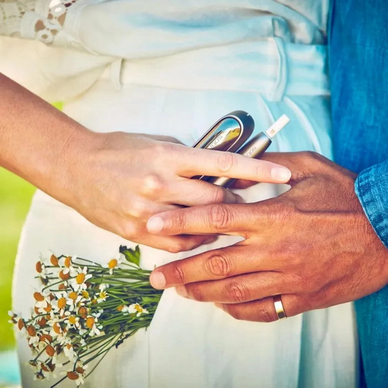 Affectionate couple holding IQOS and flowers