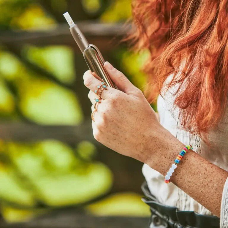 A red hair girl holds the gold IQOS