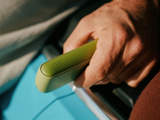 Woman's hand holding a brilliant gold IQOS 3 DUO holder and charger in a car