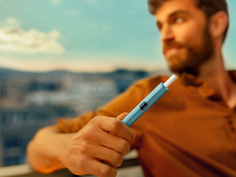 Muž držící zařízení IQOS ILUMA i v barvě Breeze Blue