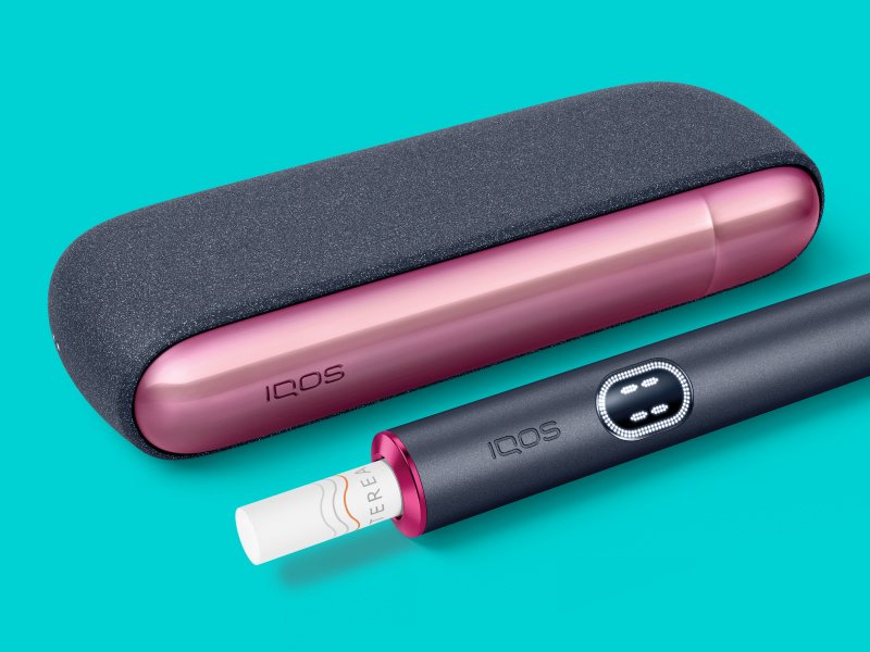 Zařízení IQOS ILUMA i poblíž své nabíječky, s uzpůsobeným předním krytem a ozdobným kroužkem