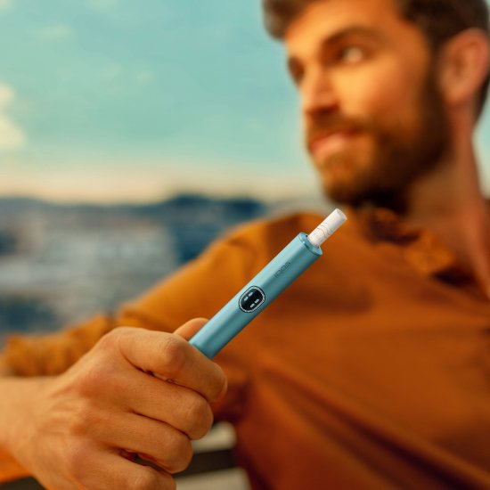 Muž držící zařízení IQOS ILUMA i v barvě Breeze Blue