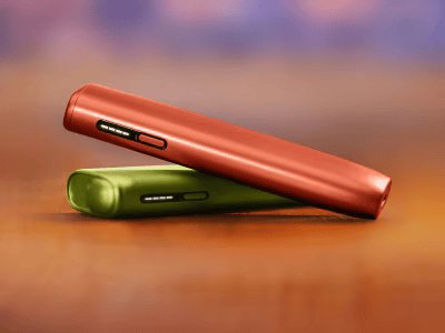 Crveni IQOS ILUMA i ONE uređaj na zelenom IQOS ILUMA i ONE uređaju