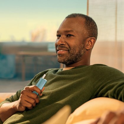 Person with green shirt holding IQOS Iluma I One device