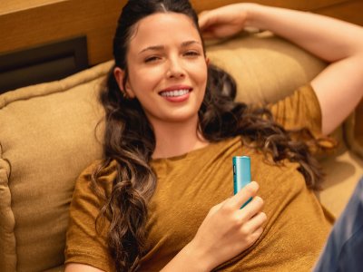 Žena ležící na gauči a držící zařízení IQOS ILUMA i ONE