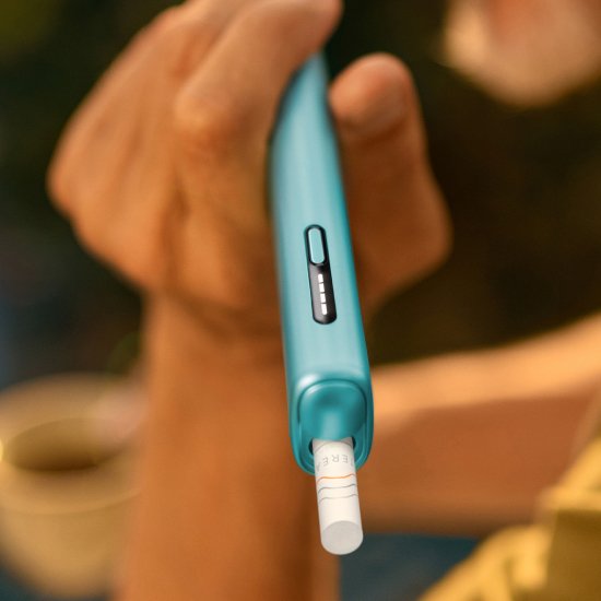 Detail of hand holding a blue IQOS ILUMA i device