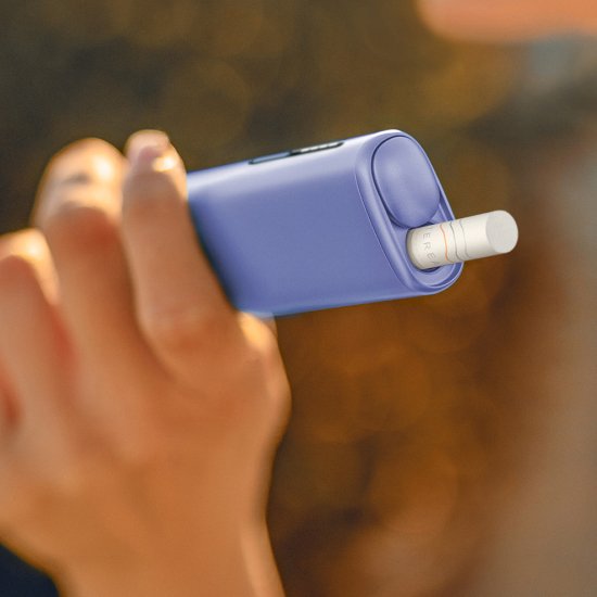 Hand holding a violet IQOS ILUMA i ONE device
