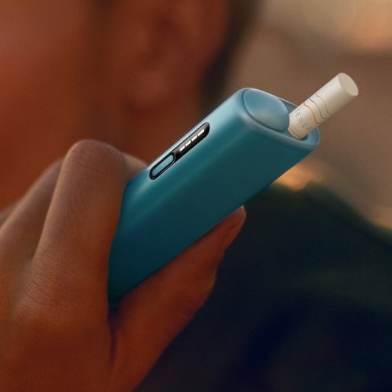 Detail of hand holding a blue IQOS ILUMA i ONE device