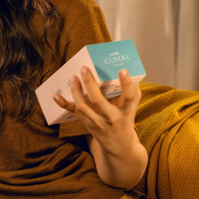 A man holding an IQOS ILUMA ONE device.