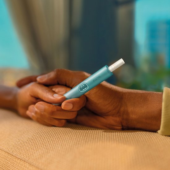 Two hands holding together an IQOS ILUMA i device