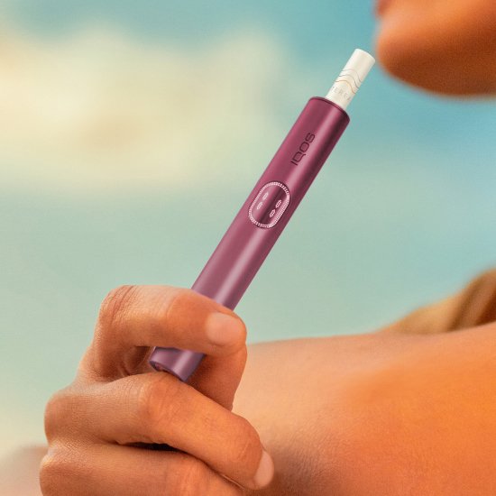 Woman holding a Garnet Red IQOS ILUMA i PRIME device
