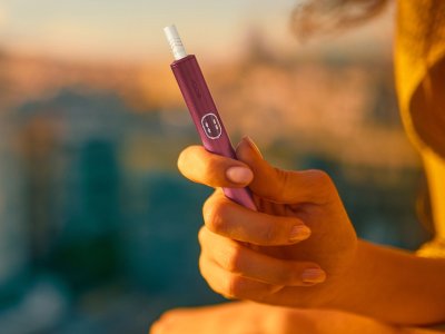 يد تحمل جهاز IQOS ILUMA i PRIME باللون النبيتي