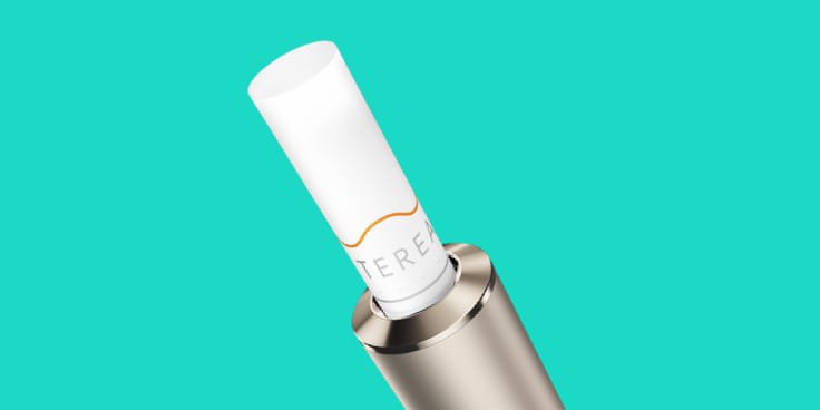 Ein jadegrünes IQOS ILUMA PRIME Gerät vor türkisem Hintergrund