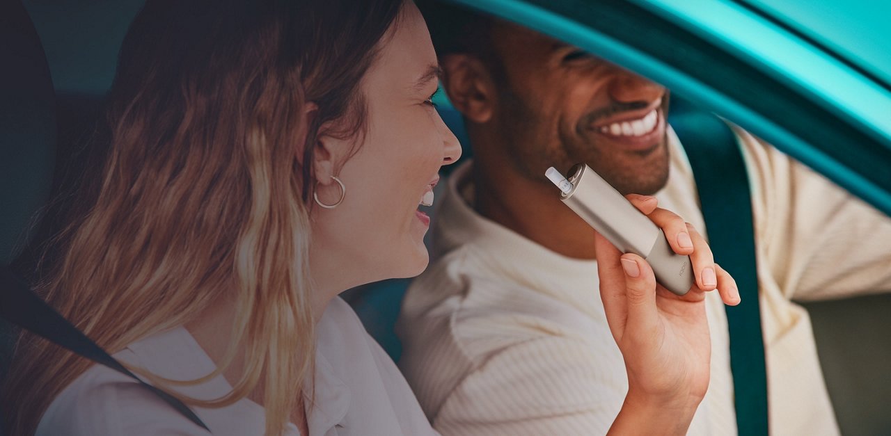 Man showing an IQOS Originals device to other people.