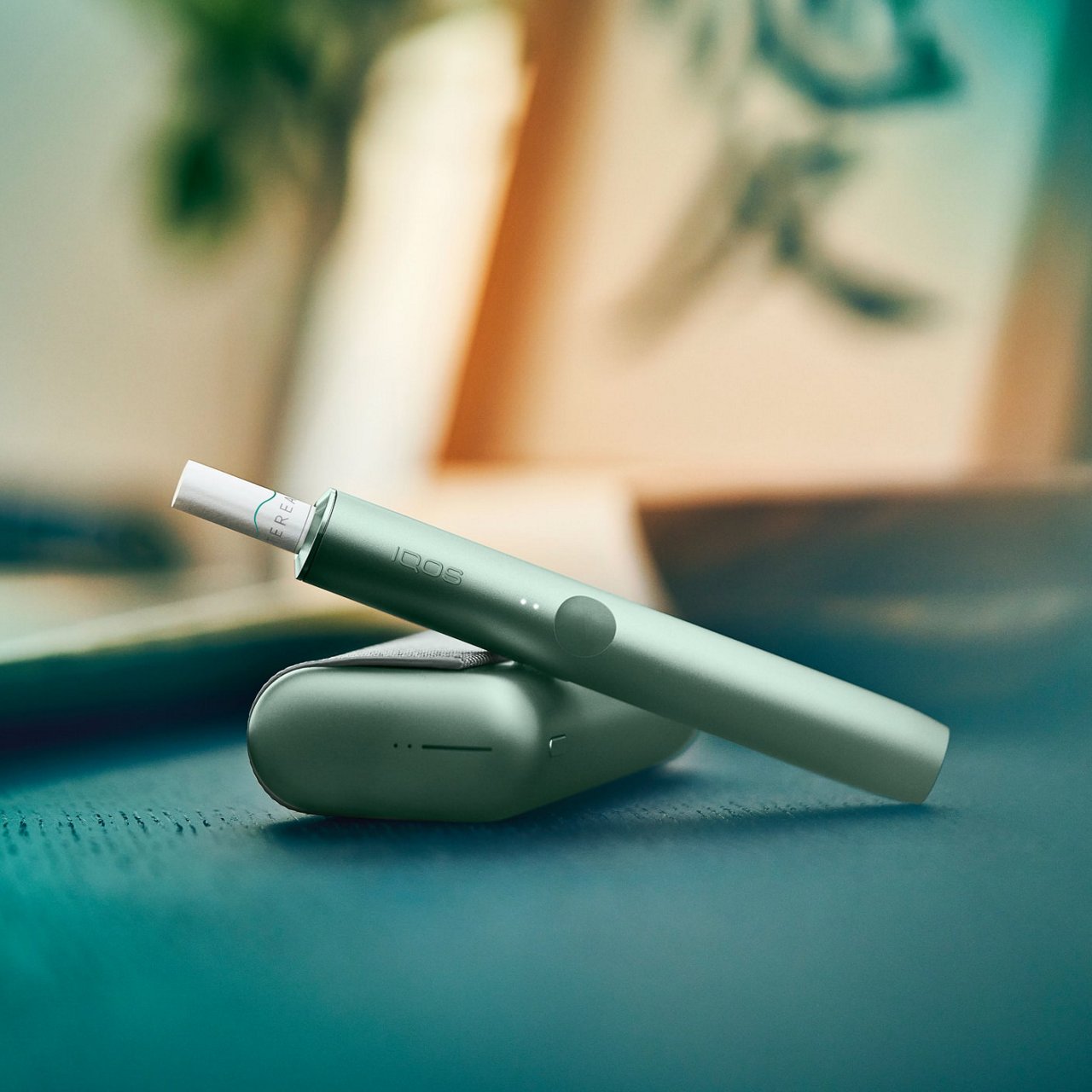 A jade green IQOS ILUMA device and holder.