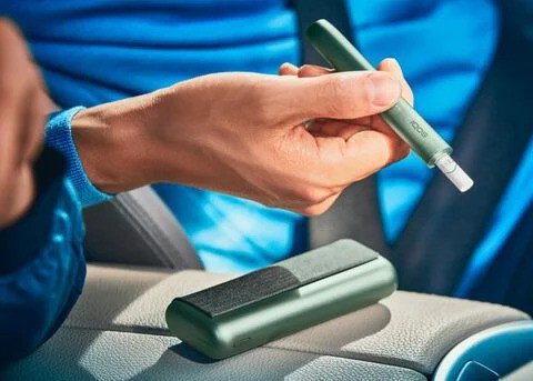 Close up of a hand holding a jade green IQOS ILUMA device.