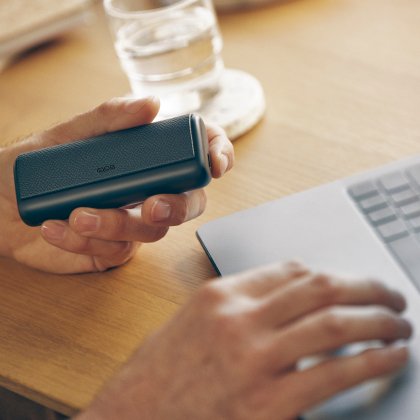 Man holding IQOS ILUMA PRIME Pocket Charger using a laptop