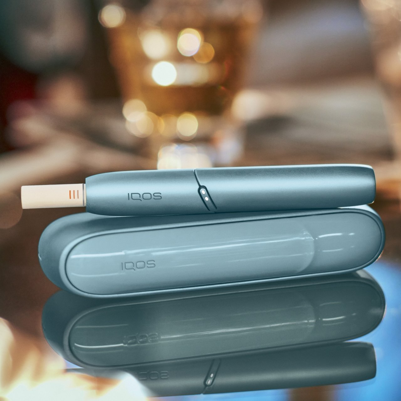 IQOS Originals Duo in turquoise auf einem glänzenden Kaffeetisch