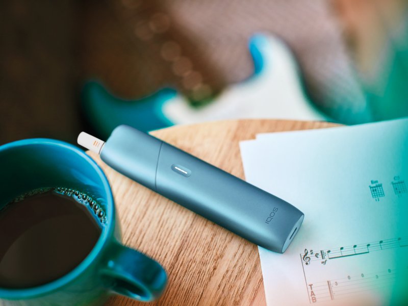 Turquoise IQOS Originals One device on a coffee table."