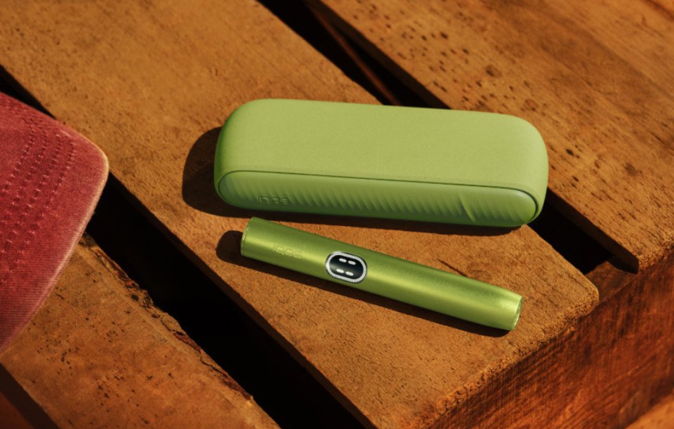 IQOS Iluma i couleur vert anis posée sur table en bois
