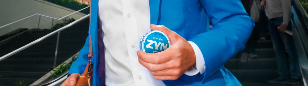 Detailný záber na muža v obleku, ktorý v ruke nesie škatuľku ZYN Cool Mint.