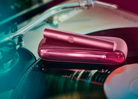 Woman's hand holding a brilliant gold IQOS 3 DUO holder and charger in a car