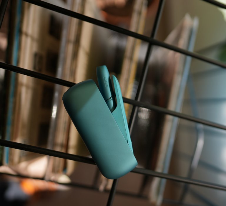 Turquoise IQOS Originals Duo  holder and pocket charger on table.