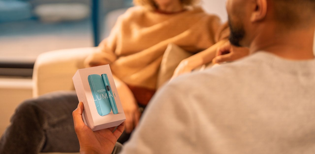 Man showing an IQOS Originals device to other people.