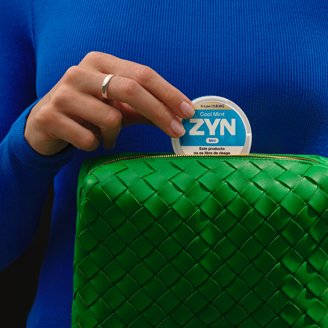 Mujer sacando de su cartera verde una lata de Zyn Cool Mint 1,5 mg