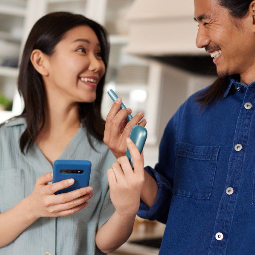 Turquoise IQOS Originals heated tobacco device, held by smiling couple