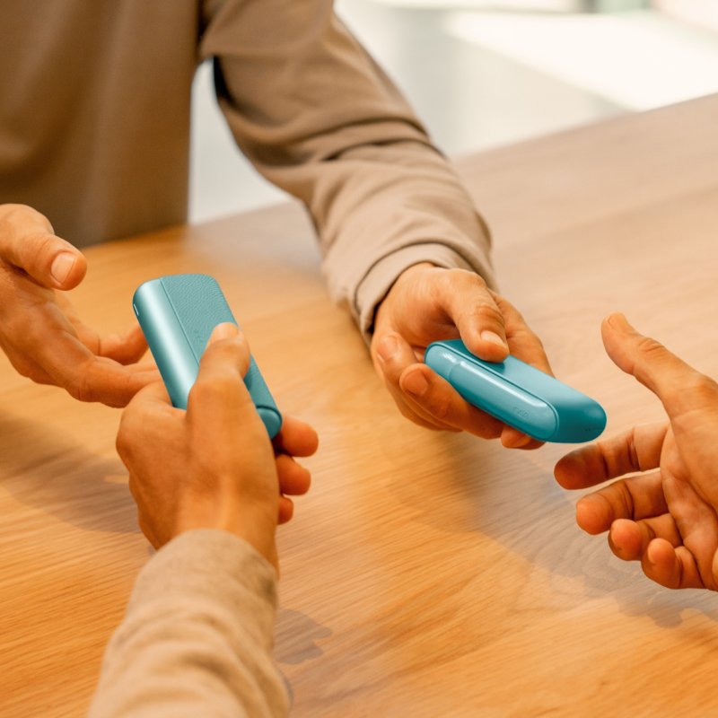 Personen übergeben sich zwei IQOS Kits.