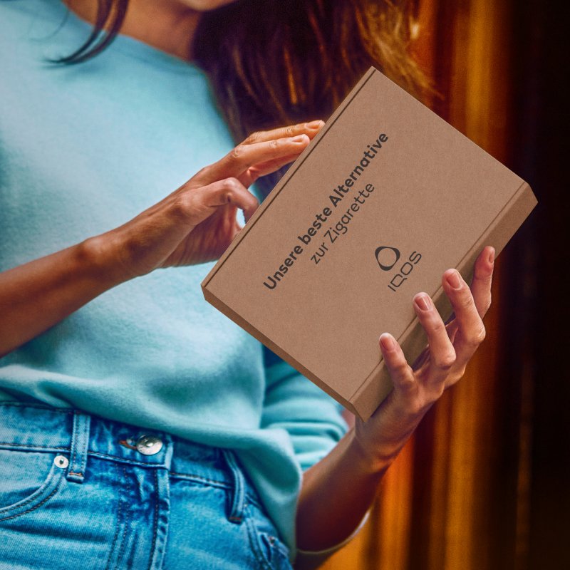 Frau hält Paket von IQOS in den Händen.