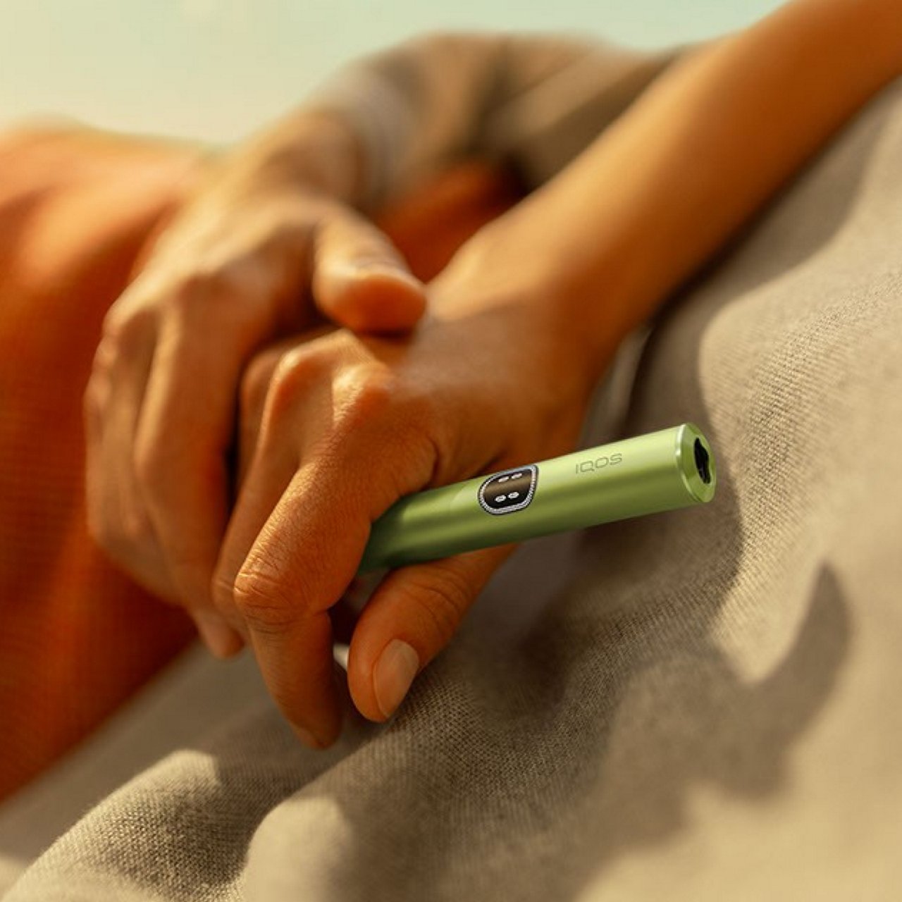 Person hält IQOS Tabakerhitzer in der Hand.